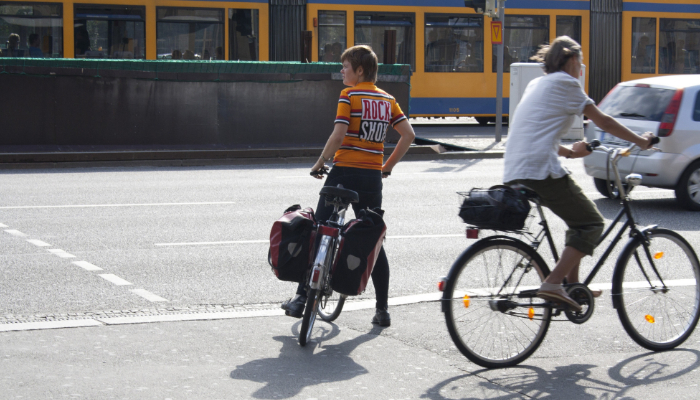 Hansaton: Two cyclists on a busy street in a city